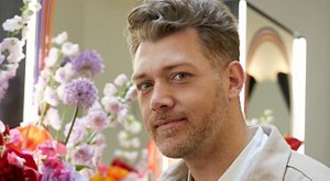 Hairdresser Michael Grey standing in front of a bouquet of flowers